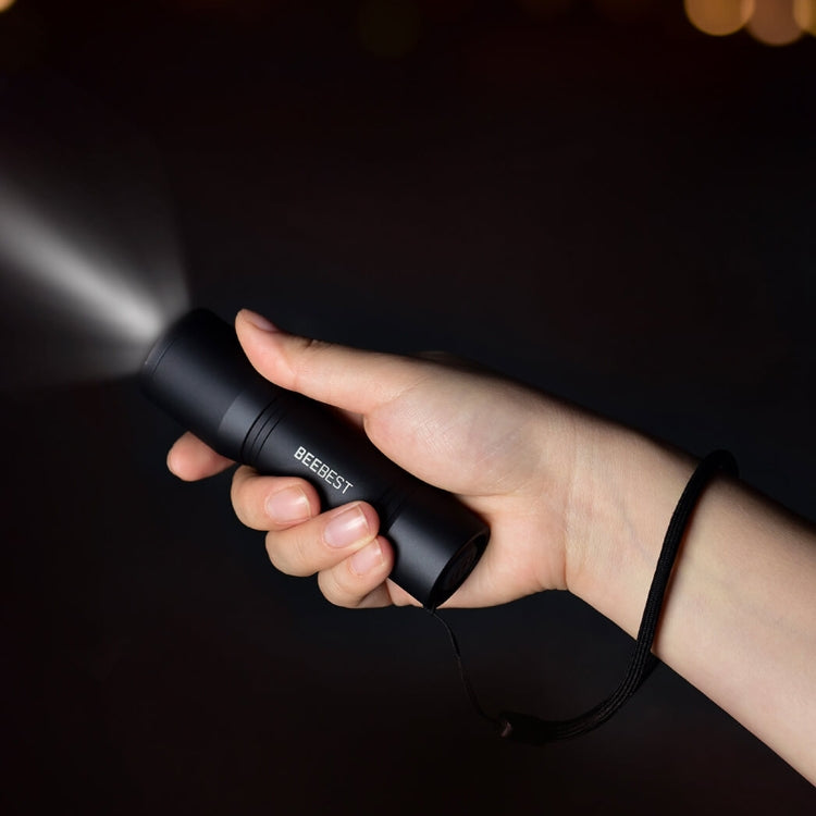 Black handheld flashlight in a person’s grip with BEEBEST logo on the barrel