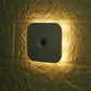 Black LED square motion sensor light lit on wall with central lens