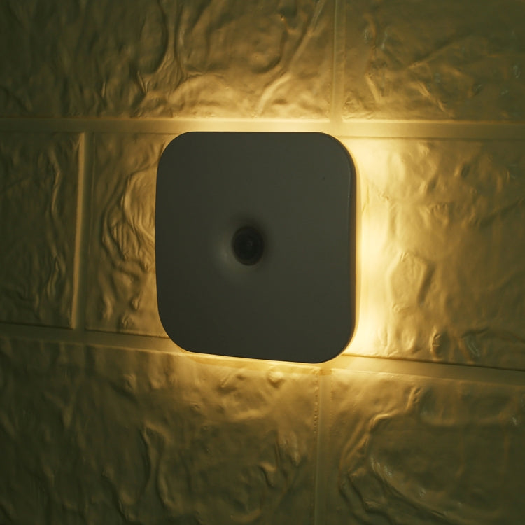 Black LED square motion sensor light lit on wall with central lens