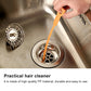 Orange drain hair cleaner hook in use, held above a sink drain