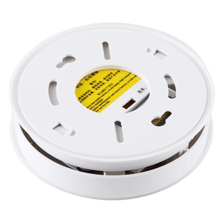 Underside of white smoke and heat detector with mounting slots and yellow label