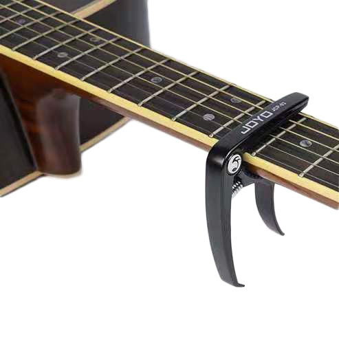 Black guitar capo clipped to fretboard with spring tension arms