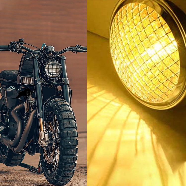 Black retro LED headlight shining bright yellow through chrome grid lens