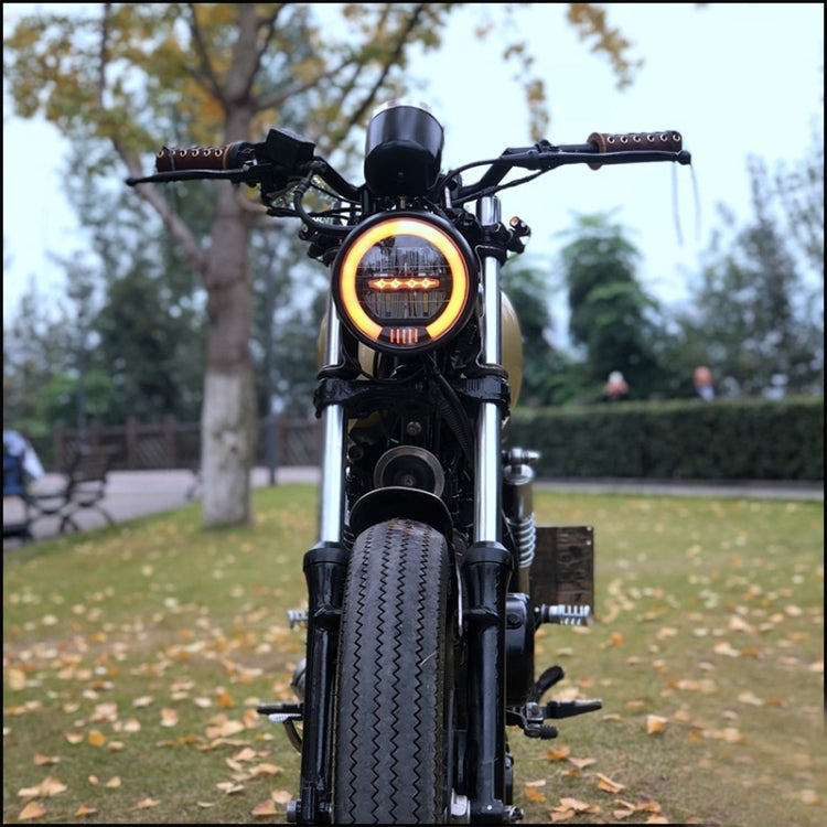 Retro motorcycle LED headlight with amber halo light on a black motorcycle front
