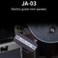 Mini guitar effects pedal with black patterned body placed near an electric amplifier.