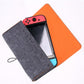 Open felt console storage bag with gray flap and orange shell, holding a handheld