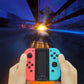 Hands holding coral and light blue Joy-Con grip charger with built-in center display