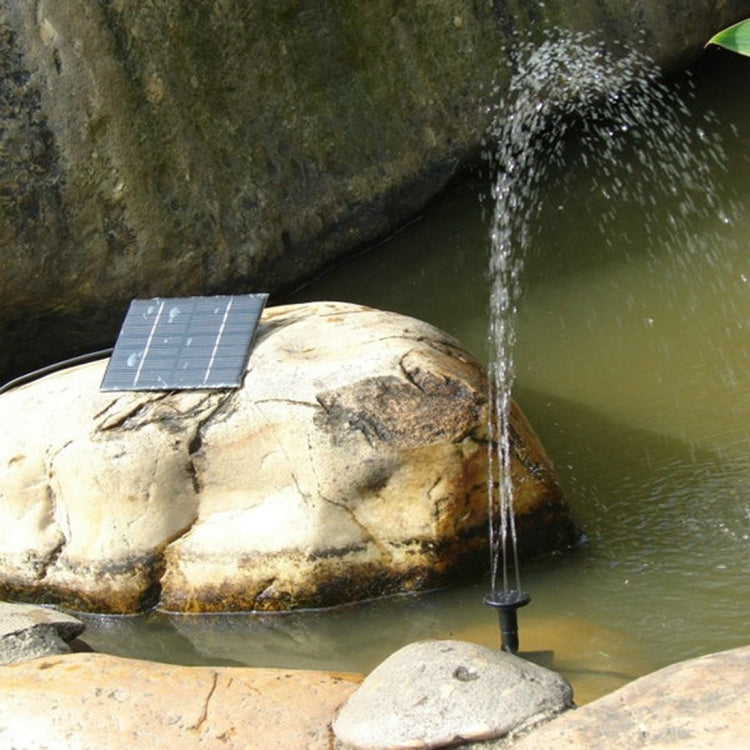 Solar water fountain pump with square solar panel and water jet nozzle by pond rocks