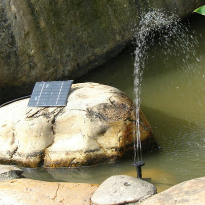 Solar water fountain pump with square solar panel and water jet nozzle by pond rocks