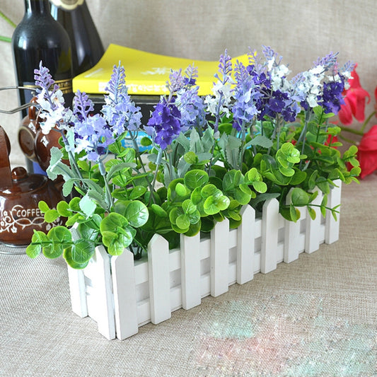 White slatted wooden flower planter with green and purple artificial blooms, fence-style.