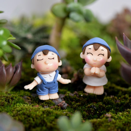Blue hooded dollhouse garden ornament figures on moss micro landscape with small plants
