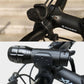 Bike flashlight clamp and light unit on handlebars in black, with cable wiring visible