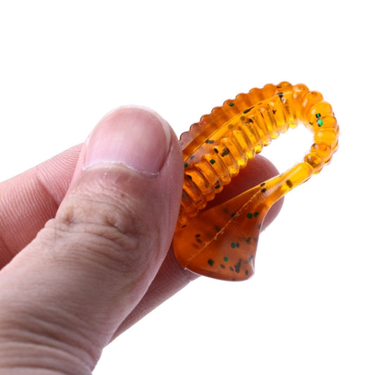 Close-up of hand holding an orange ribbed screw-tail soft fishing lure