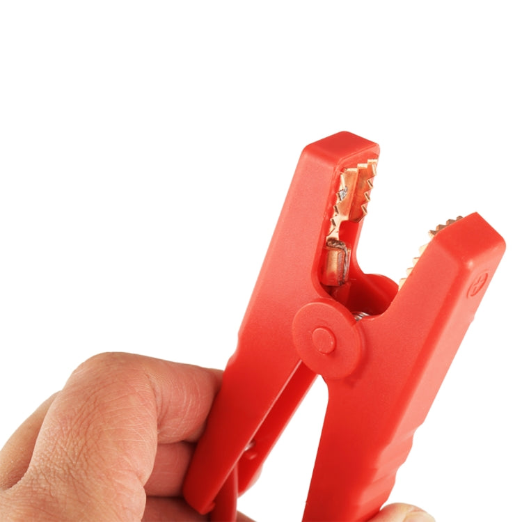 Red battery clamp jaw held open by hand, showing metal contact points