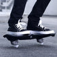 Two-wheel flash skateboard under sneakers, black deck with silver trucks and wheels