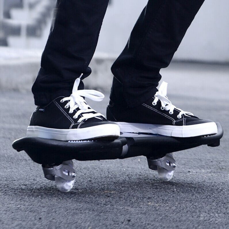 Two-wheel flash skateboard under sneakers, black deck with silver trucks and wheels