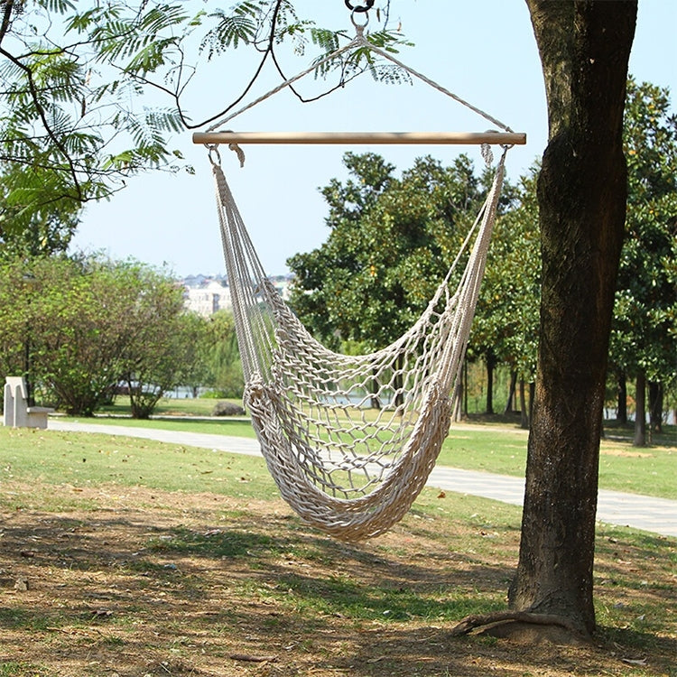 Cotton rope net hammock swing with wooden spreader, hanging between trees