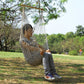 Rope net hammock swing with a seated person, suspended outdoors from trees