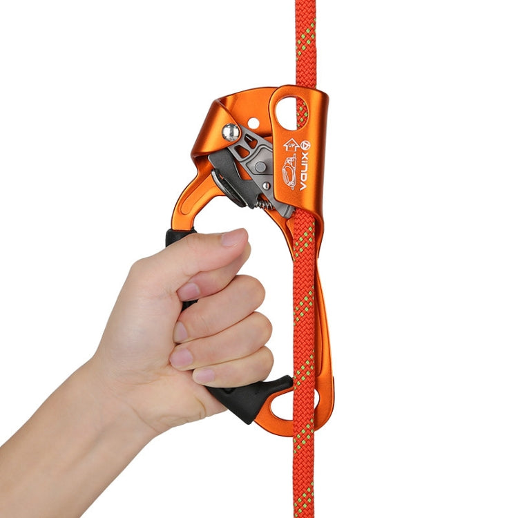 Handheld left-hand rope gripper held in hand, orange body with black trigger and rope.