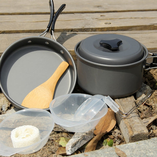 Camping cookware set with two dark gray pots, black lid, and wooden-handled utensil