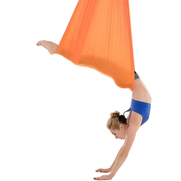 Orange aerial yoga hammock set, side view with person performing overhead stretch