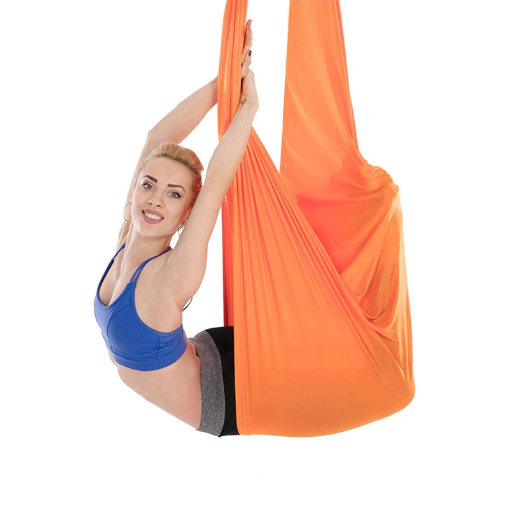 Orange aerial yoga hammock set, person holding elastic straps during aerial stretch