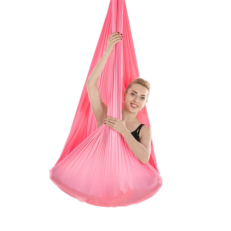 Pink aerial yoga hammock with mesh fabric, person in a hanging seated pose