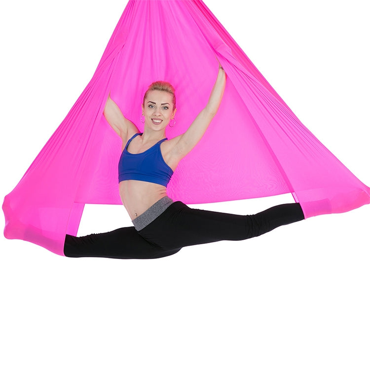 Bright pink aerial yoga hammock with mesh canopy, person holding side straps