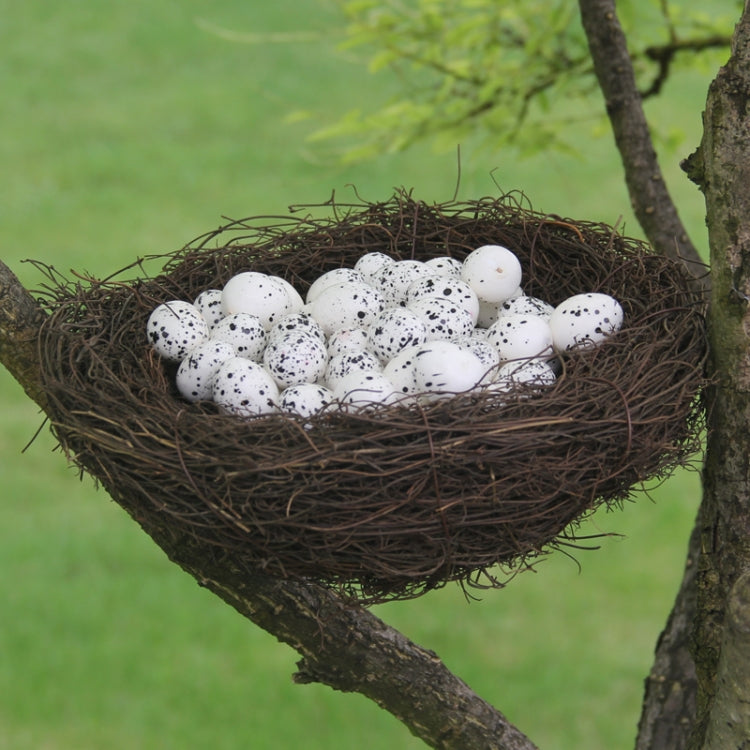 Brown straw bird nest with speckled white eggs on tree branch
