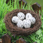 Simulated bird nest decoration holding six white speckled eggs