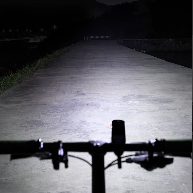 Bicycle front headlight shining a wide white beam on the road