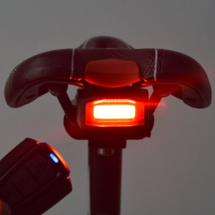 Bike tail light under saddle with bright red glow and handheld remote nearby