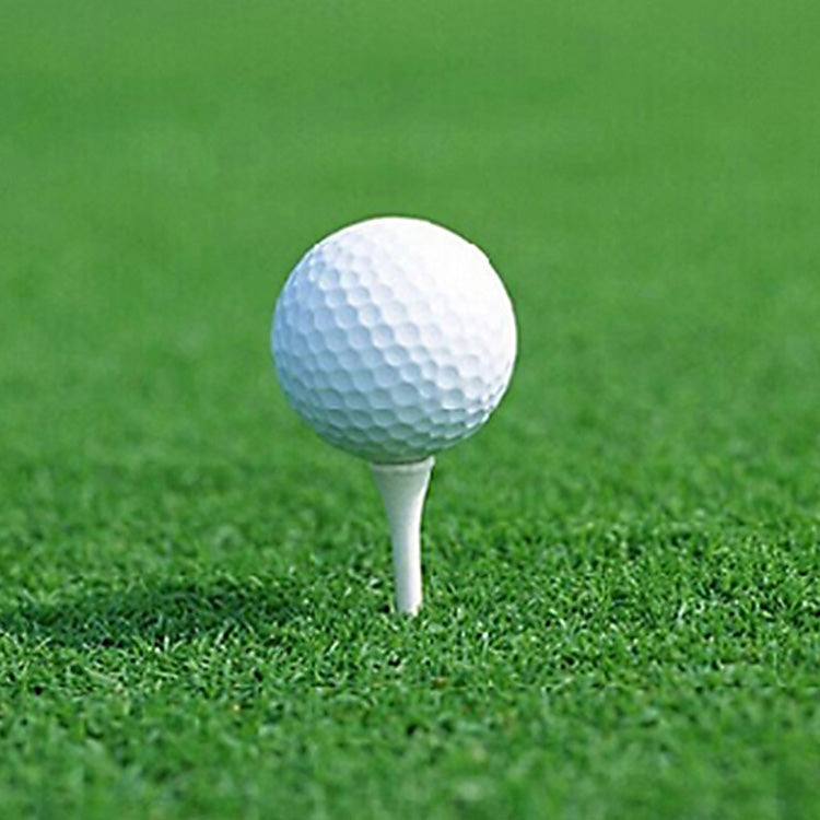 White rubber golf ball on a tee, standing on green grass