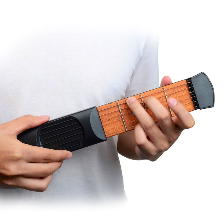 Mini guitar chord trainer held by hands over wood-tone fretboard panel