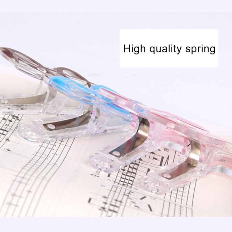 Close-up of a music note spring page clip with clear body and blue note accent