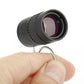 Black mini telescope held in hand, showing front lens with purple glass