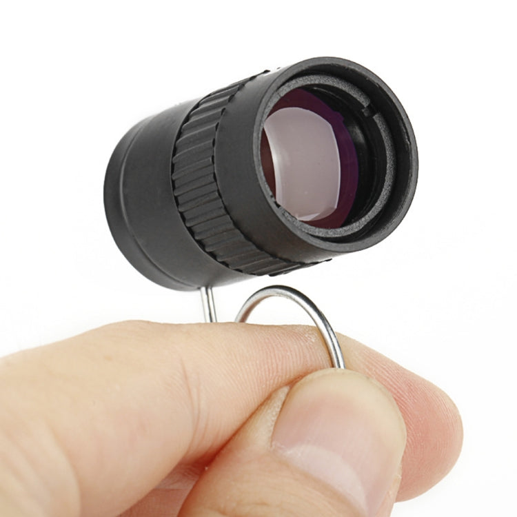 Black mini telescope held in hand, showing front lens with purple glass