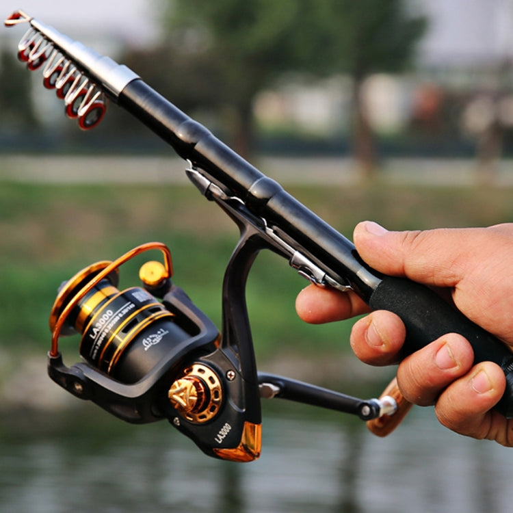 Hand holding black telescopic rod near reel with line guides and cork grip