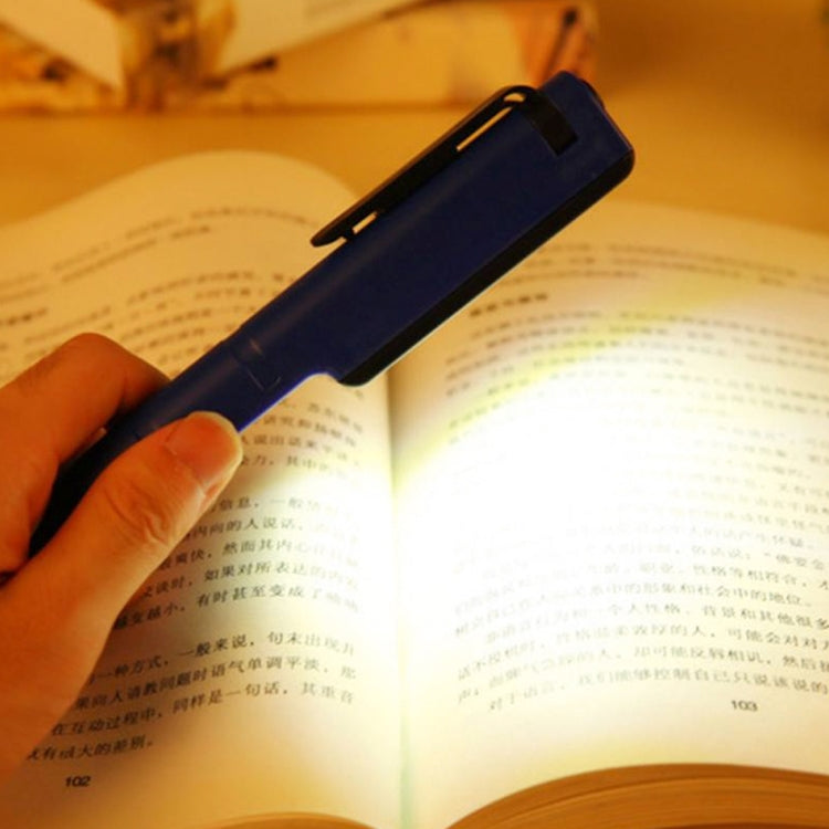 Black COB LED pen light switched on near an open book