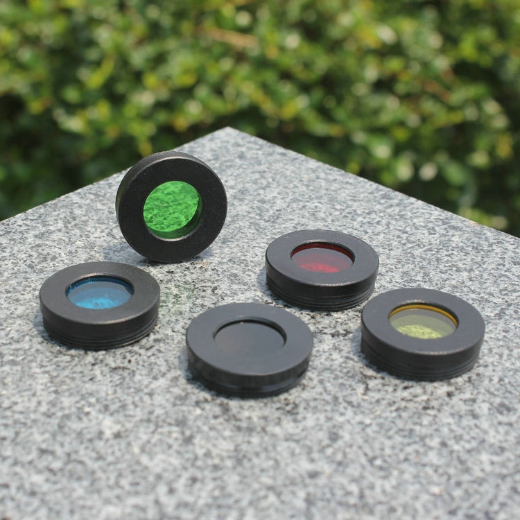 1.25-inch telescope color filters assorted on a stone surface, green and blue visible