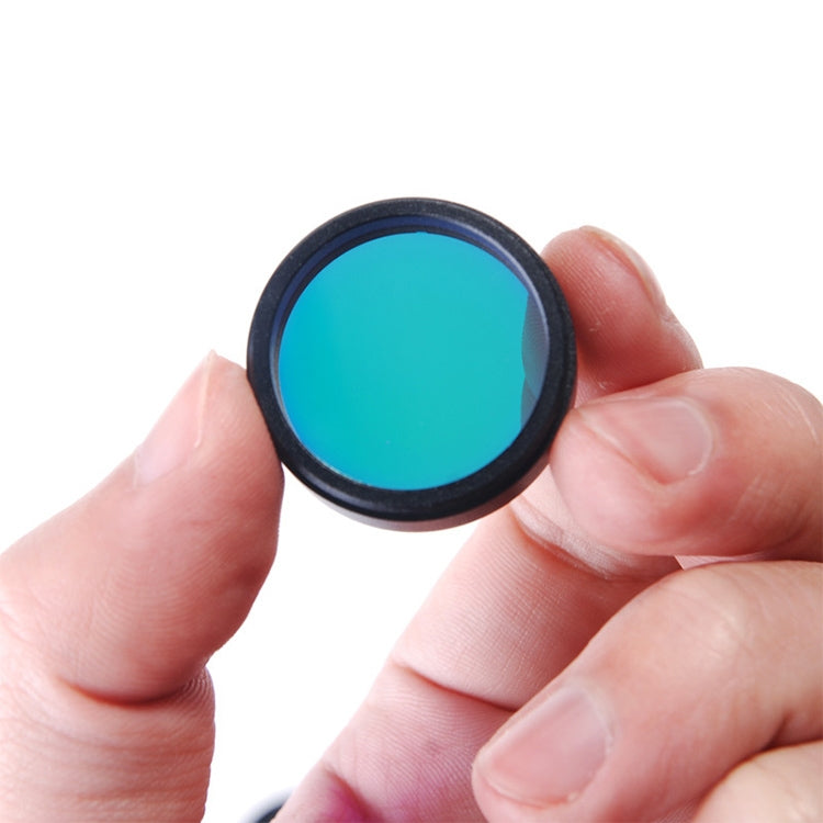 UHC filter held by fingers; circular blue-green tinted lens with black rim