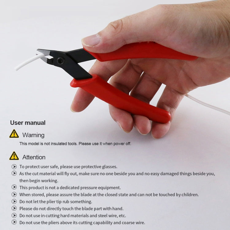 Diagonal cutter nippers with red handles held in hand; black head and jaws