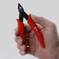 Diagonal plastic cutter nippers with red grips and black jaws, held by hand