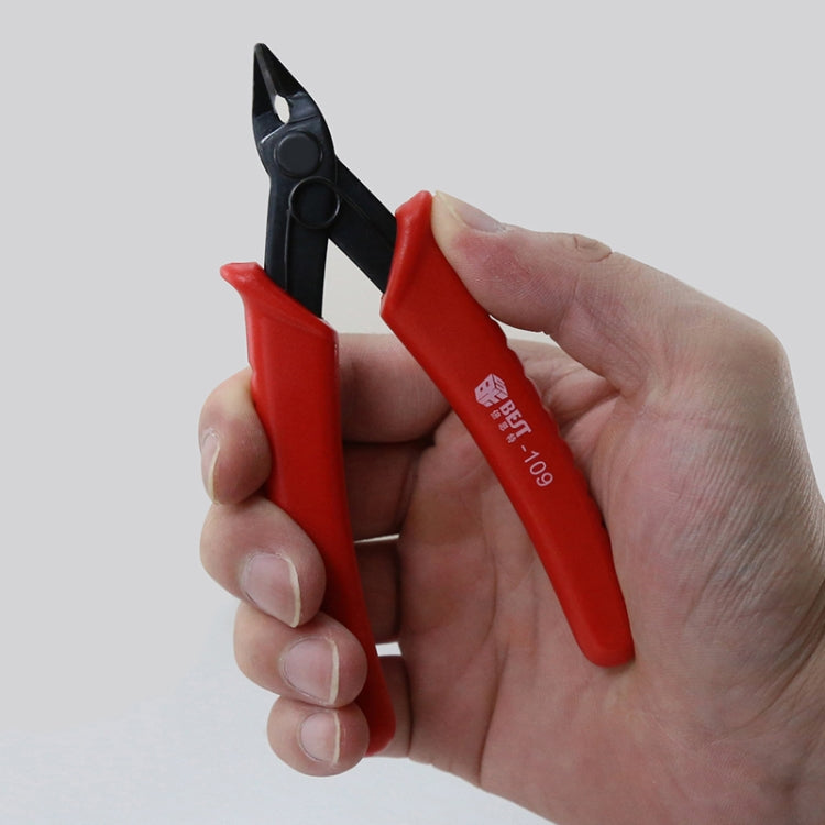 Diagonal plastic cutter nippers with red grips and black jaws, held by hand