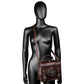 Brown leather-look crossbody bag on black mannequin with long strap and gear front emblem