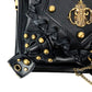 Black bag detail with gold studs, braided trim, and blue gem emblem on textured leather