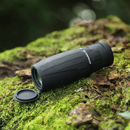 Black monocular with lens cap on mossy ground