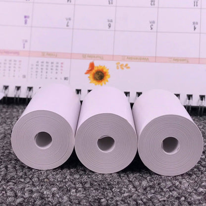Thermal label printer paper rolls, three gray-white backing rolls on a surface