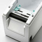 Open thermal label printer showing the internal print roller and label path, white housing