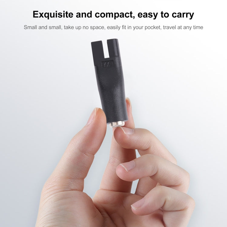 Black DC shaver interface converter held in hand, compact plug adapter